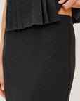 Black skirt with pleated top on a neutral background
