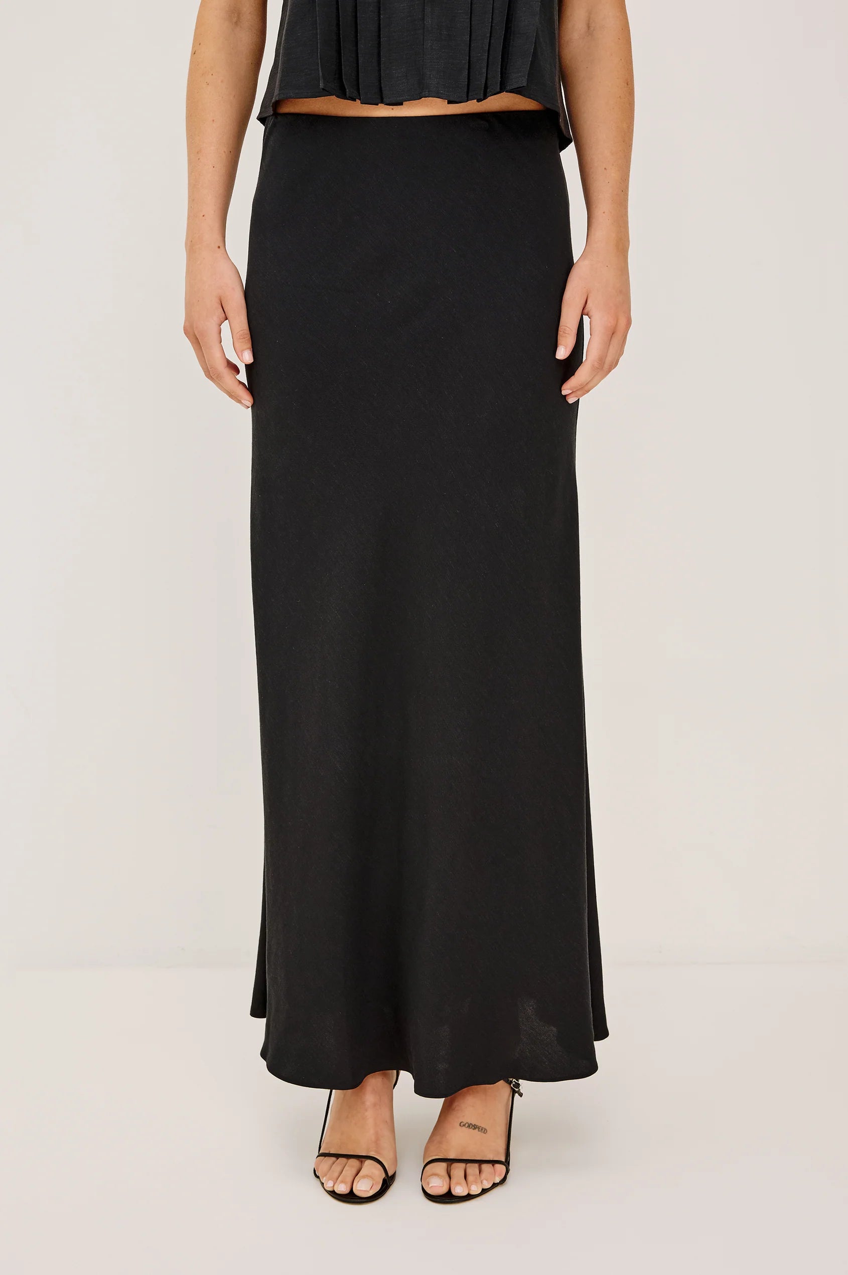 Person wearing a black skirt on a plain background
