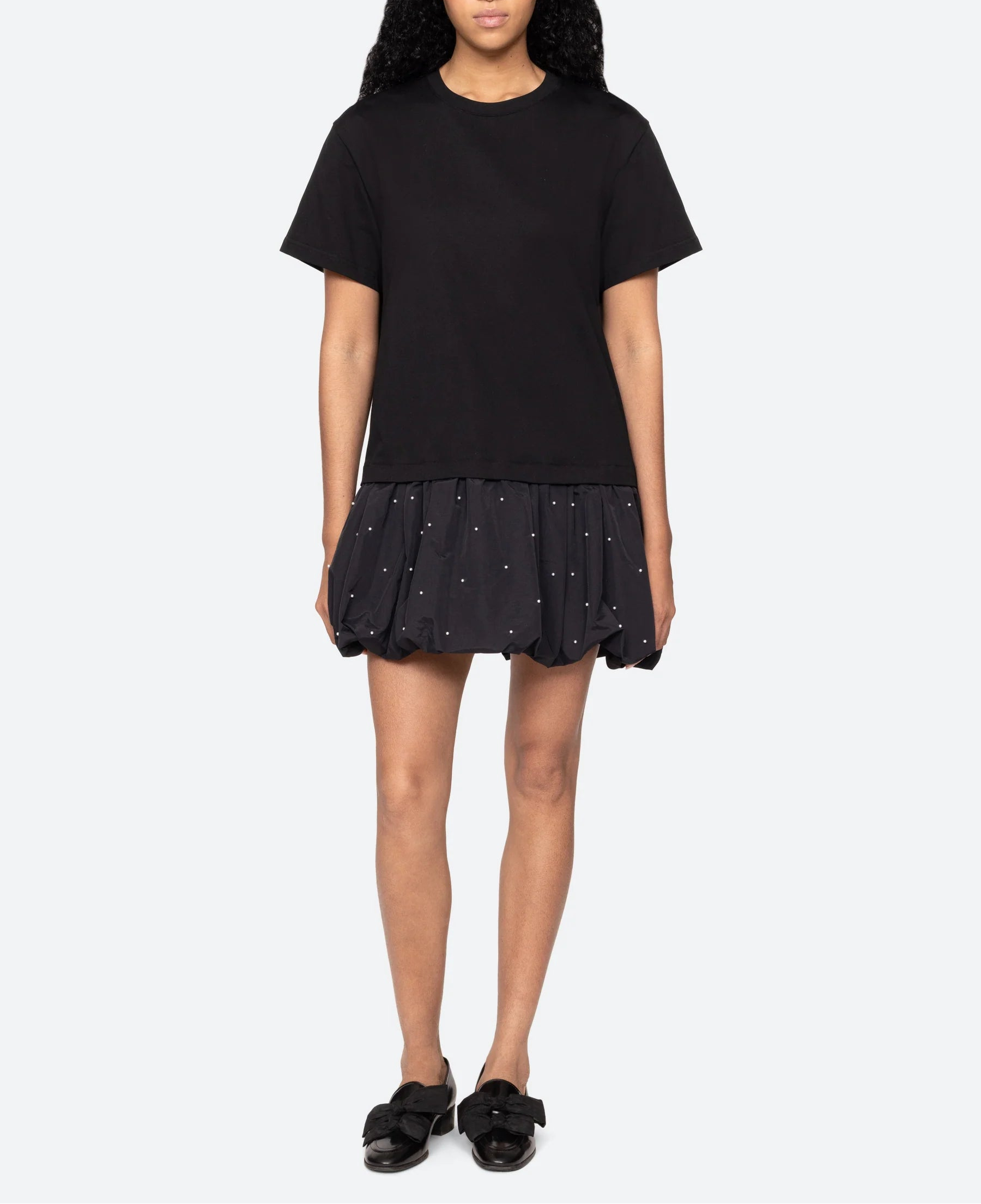 Person wearing a black outfit with a skirt on a white background