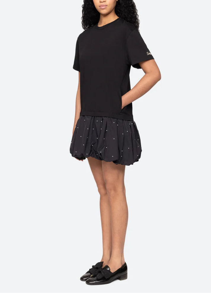 Woman wearing a black t-shirt and black skirt with white polka dots on a white background