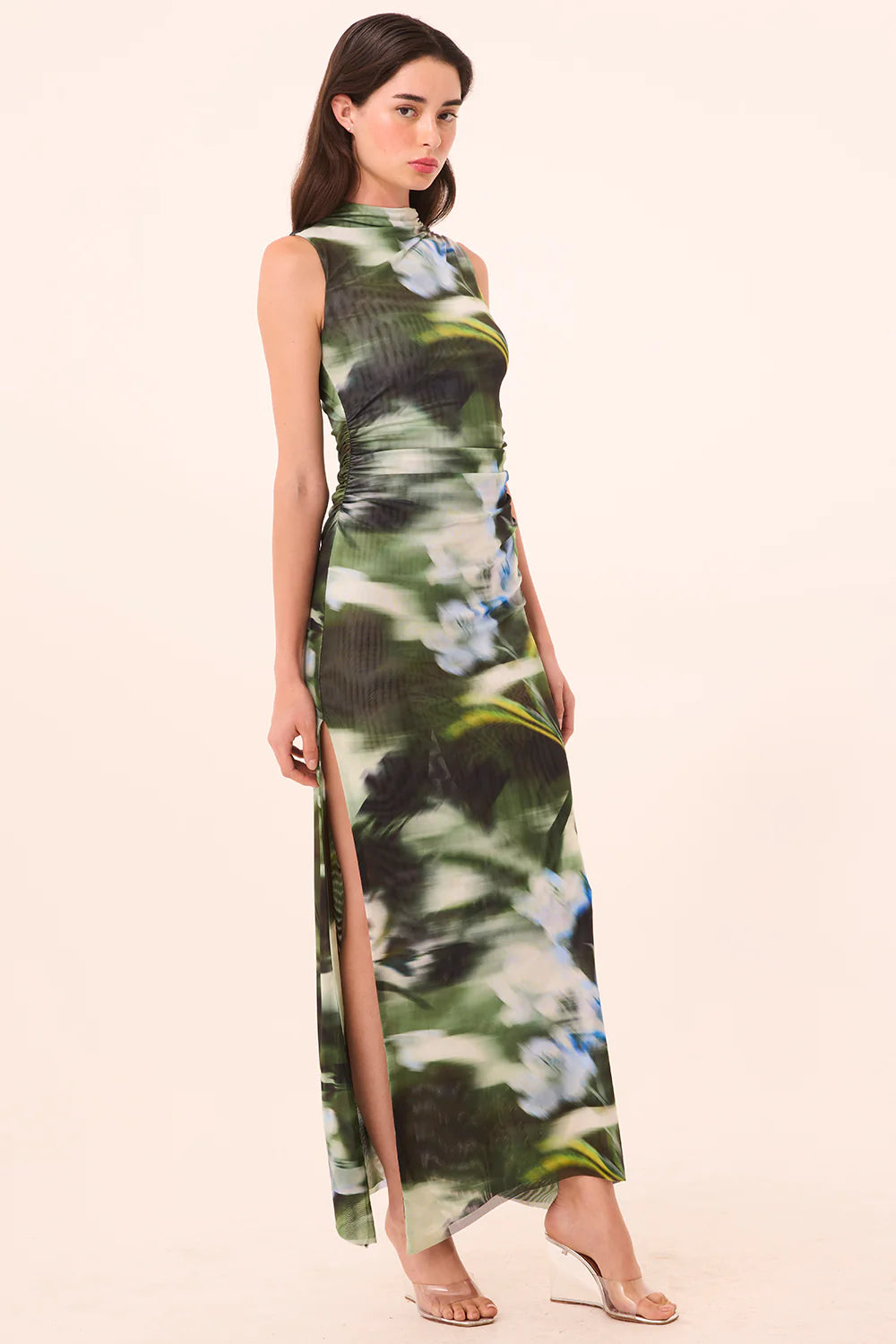 Woman wearing a floral dress with a slit on a beige background
