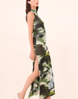 Woman wearing a green floral dress with a slit on a beige background