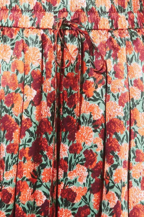 Close-up of a pleated skirt with an orange, red, and green floral print and a matching drawstring waist.