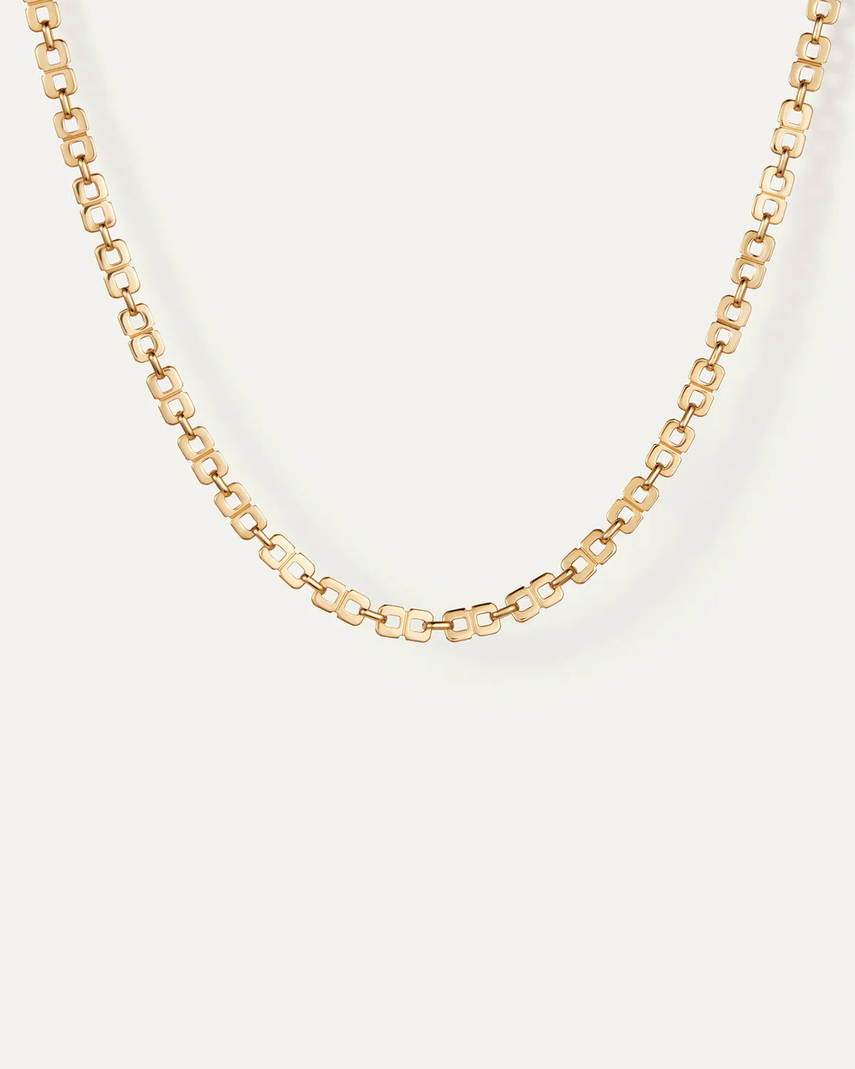 Gold chain necklace on a light beige background