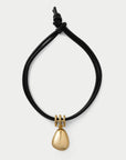 A black adjustable cord bracelet with a polished gold teardrop pendant and gold ring details, shown on a light gray background.