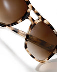 Close-up of tortoiseshell sunglasses with brown tinted lenses on a clean white background.