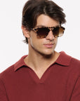 A man wearing tortoiseshell aviator-style sunglasses with brown lenses and a textured burgundy knit polo shirt, photographed against a clean white background.