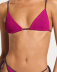 model wearing a magenta bikini on white background
