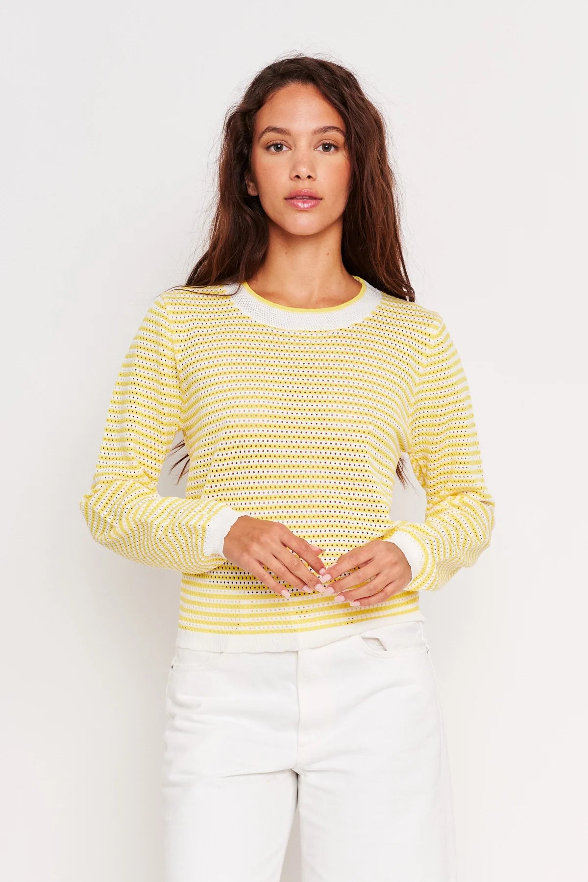 Woman wearing a yellow textured sweater against a white background