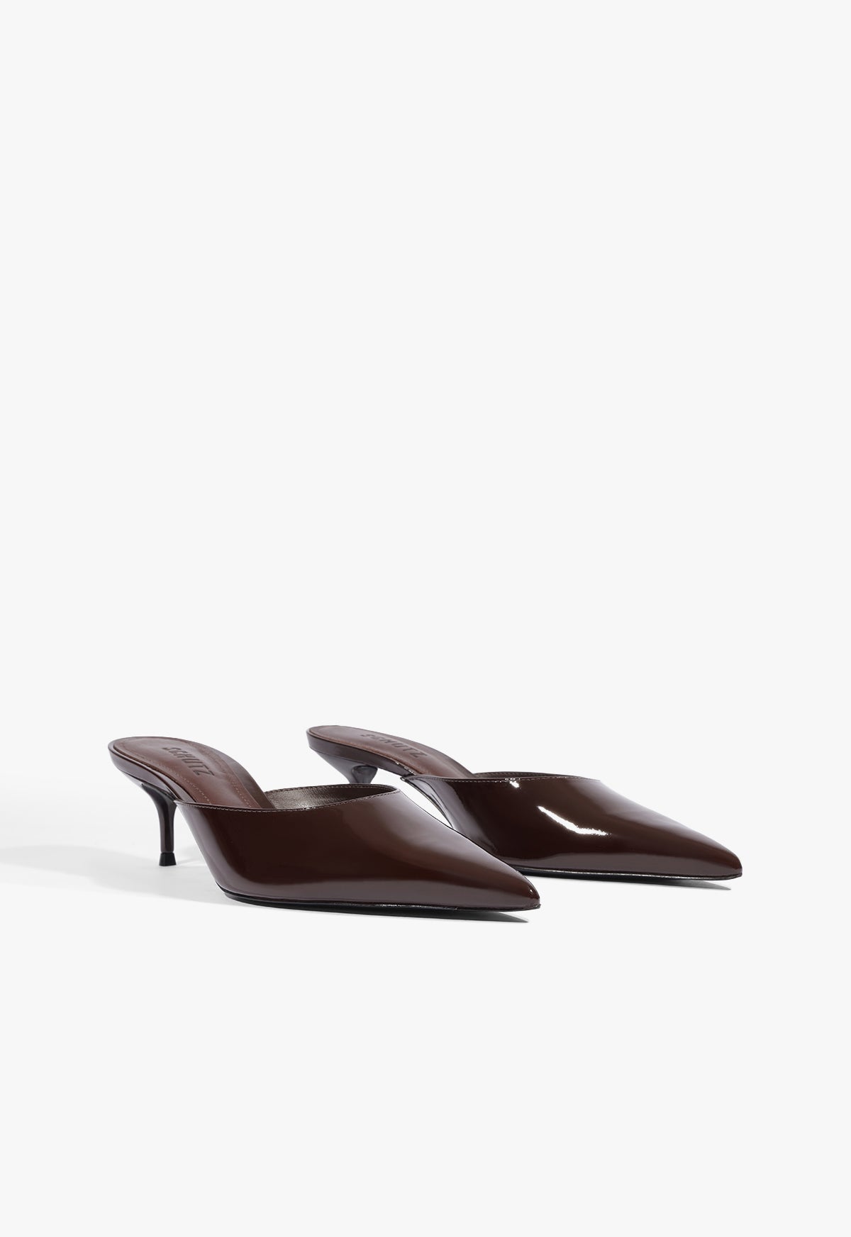 A pair of dark brown patent leather pointed-toe mule heels with slim kitten heels, displayed on a clean white background.