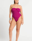 model wearing a pink one piece bathing suit on white background