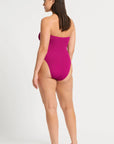 model wearing a pink one piece bathing suit on white background, back view