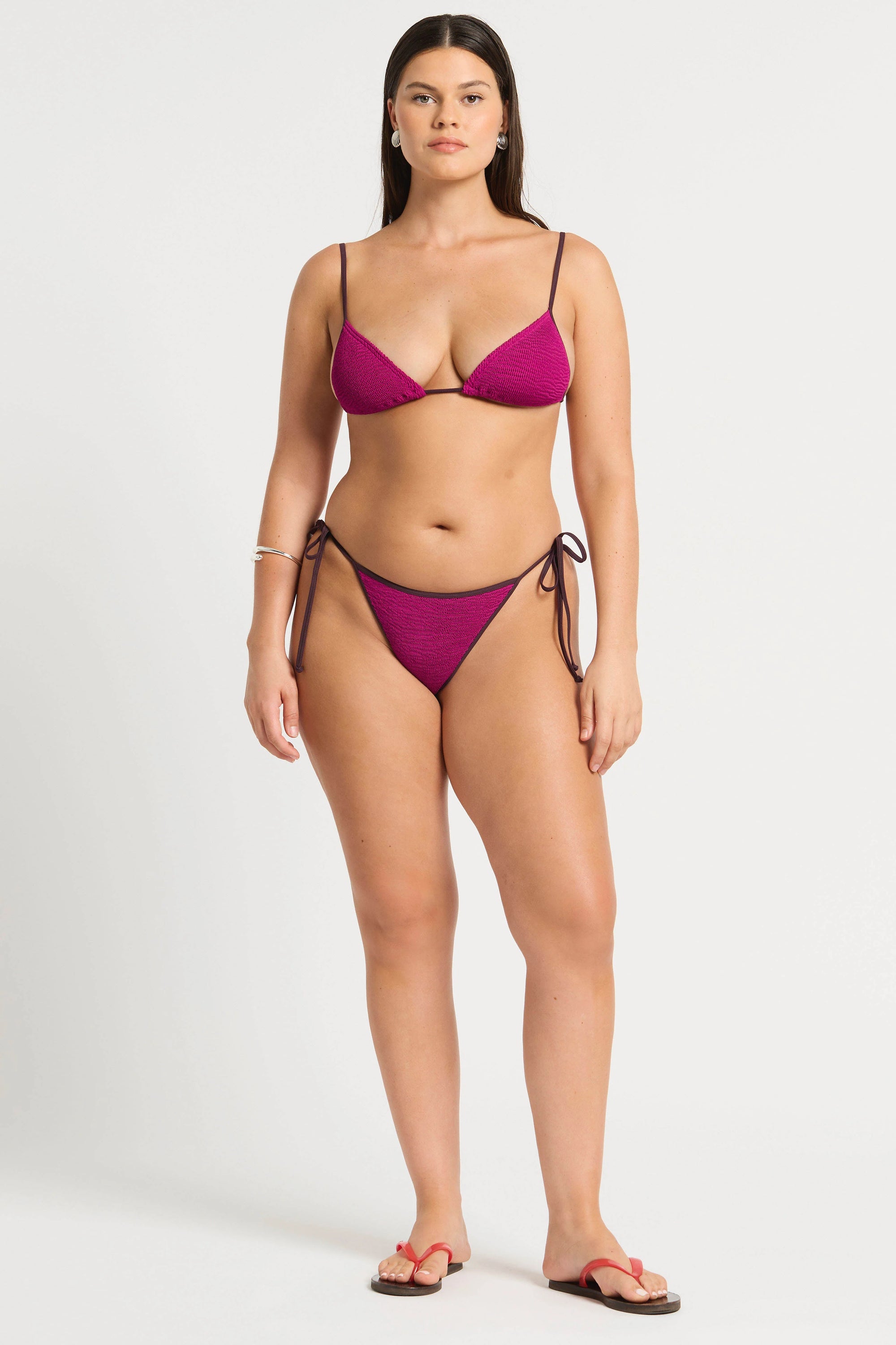 model wearing a magenta bikini on white background