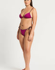 model wearing a magenta bikini on white background