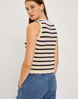 Woman wearing a black and white striped sleeveless top with blue jeans on a plain background