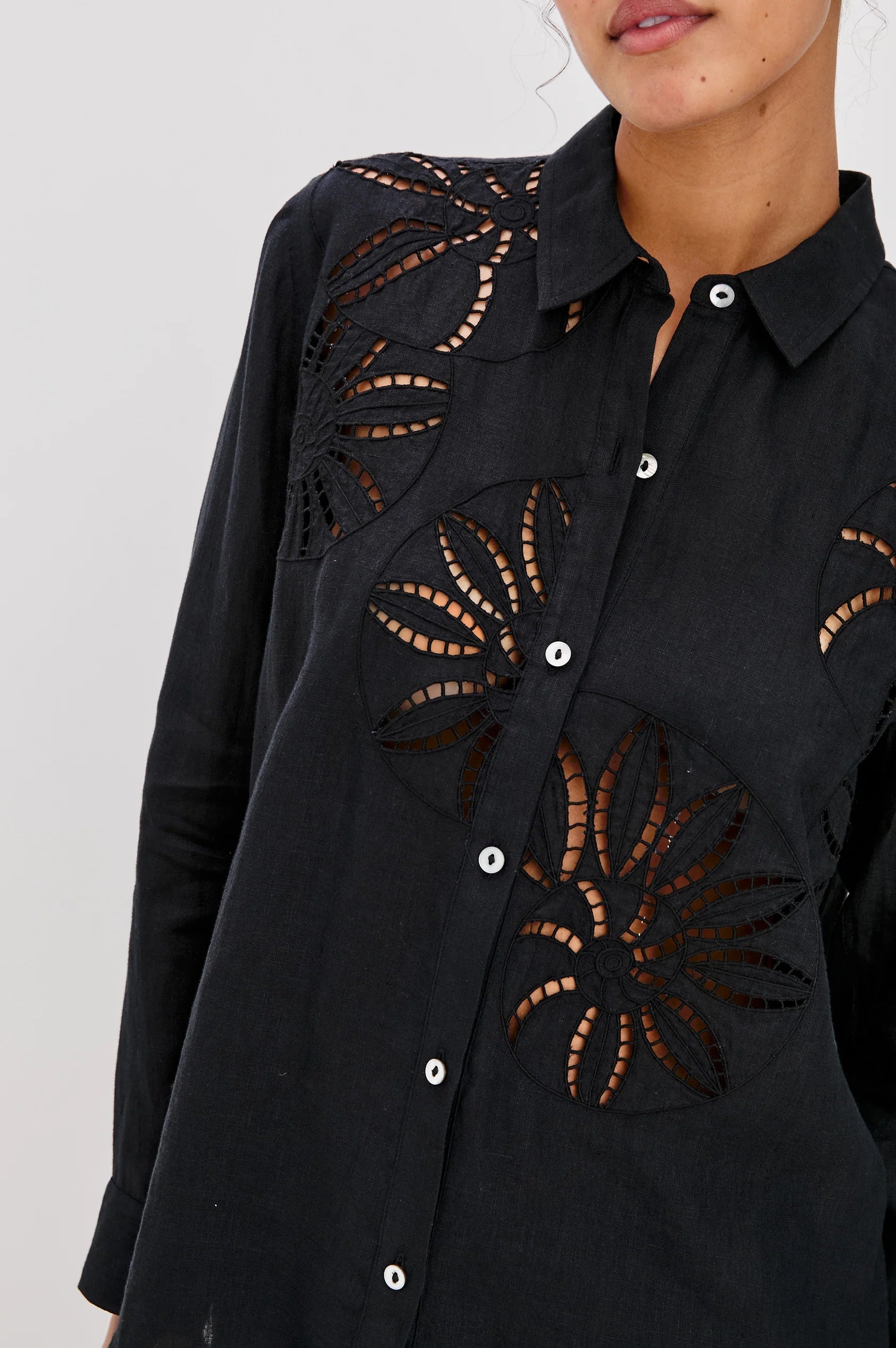 Black shirt with cut-out designs on a white background detail view