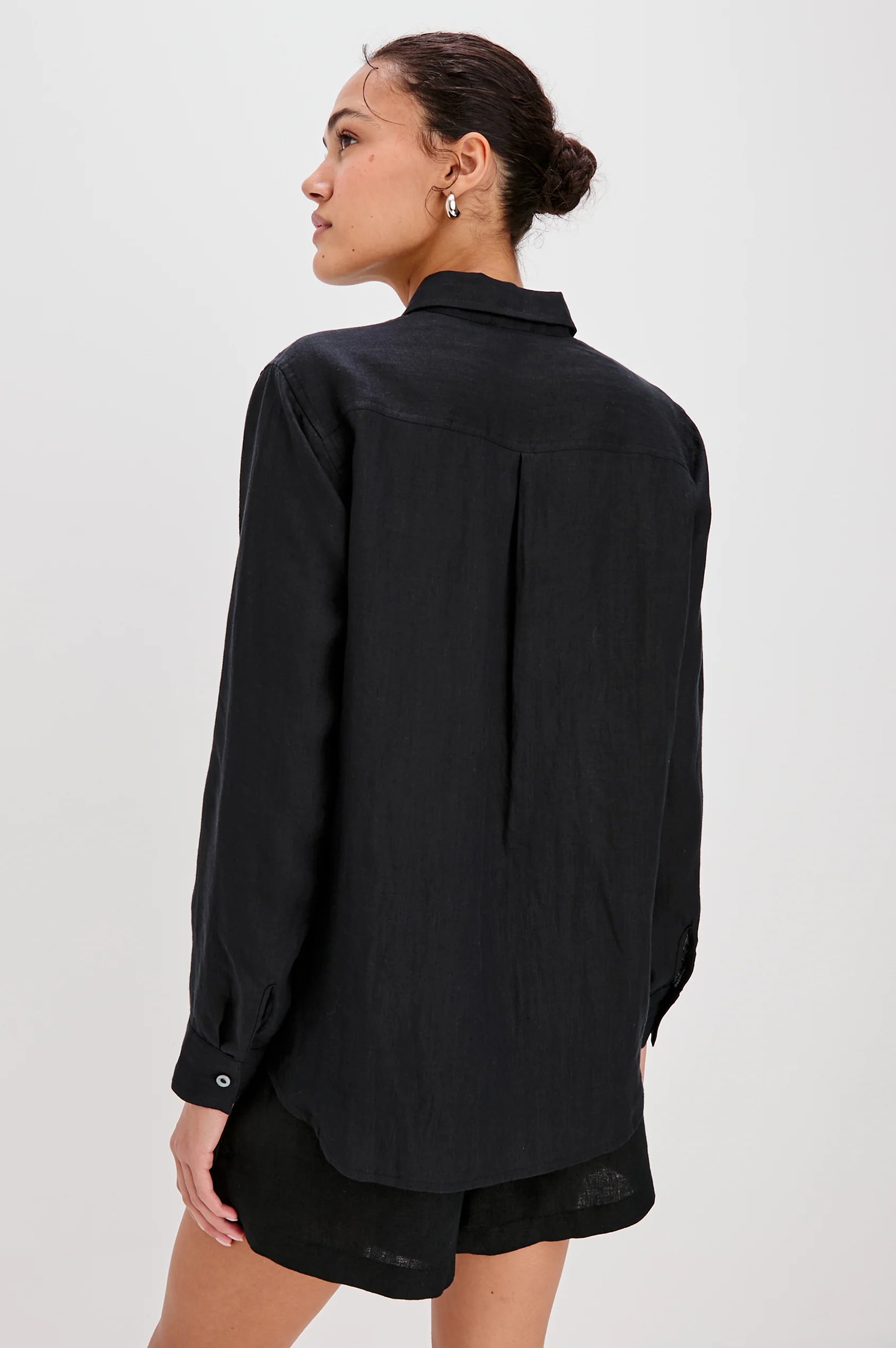 Person wearing a black shirt and shorts on a white background back view