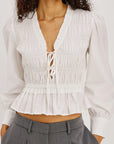 Woman wearing a white blouse with a deep neckline and gray pants on a white background