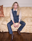 Woman sitting on a beige couch wearing a denim outfit.