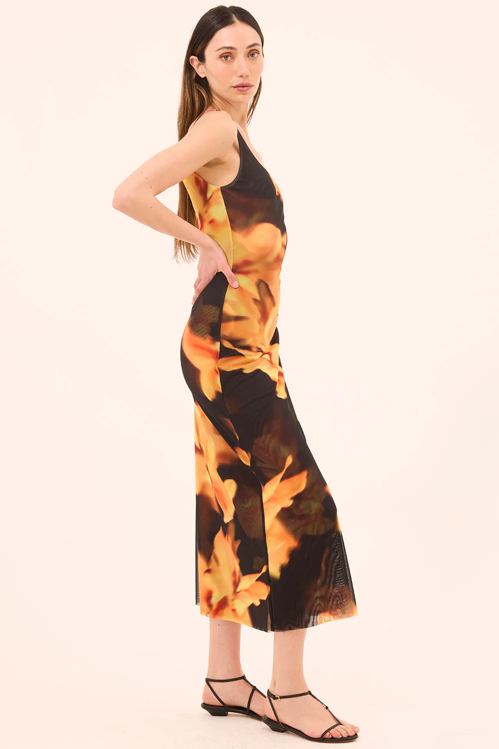 Woman wearing a sleeveless dress with a floral pattern on a beige background