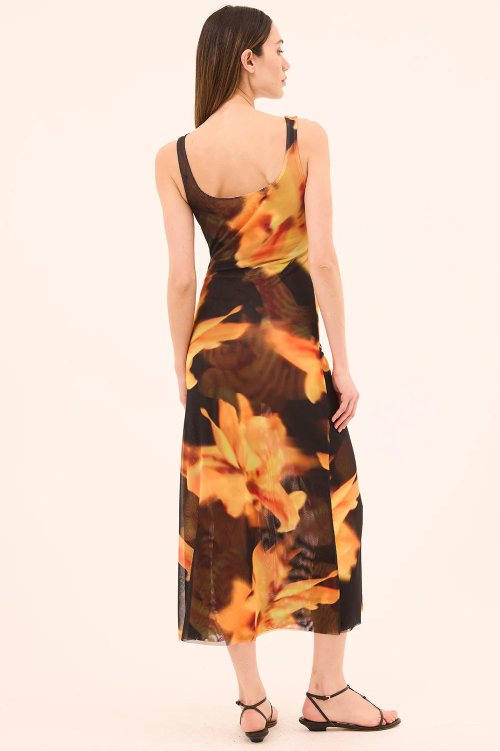 Woman wearing a floral dress with a neutral background back view