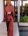 Person wearing a brown satin outfit standing by a poolside.