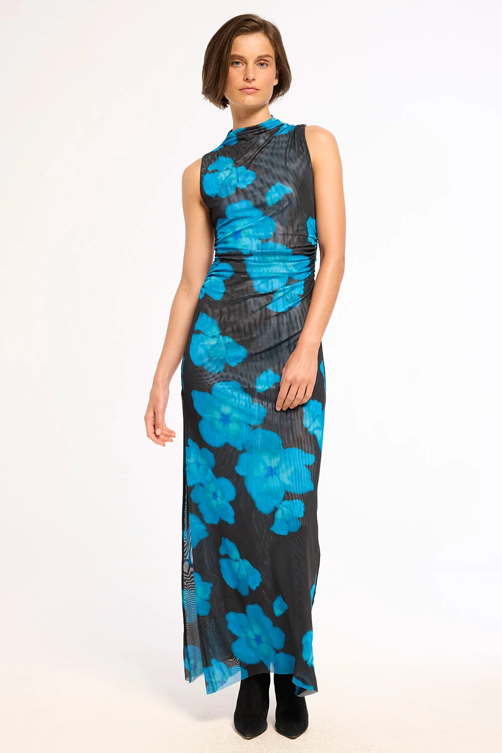 A sleeveless high-neck maxi dress with a black base and a vibrant blue floral pattern, modeled against a plain white studio background.
