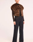 A model is shown from the back wearing a brown fur-look cropped vest over a black lace long-sleeve top and dark blue wide-leg jeans, against a plain light background.