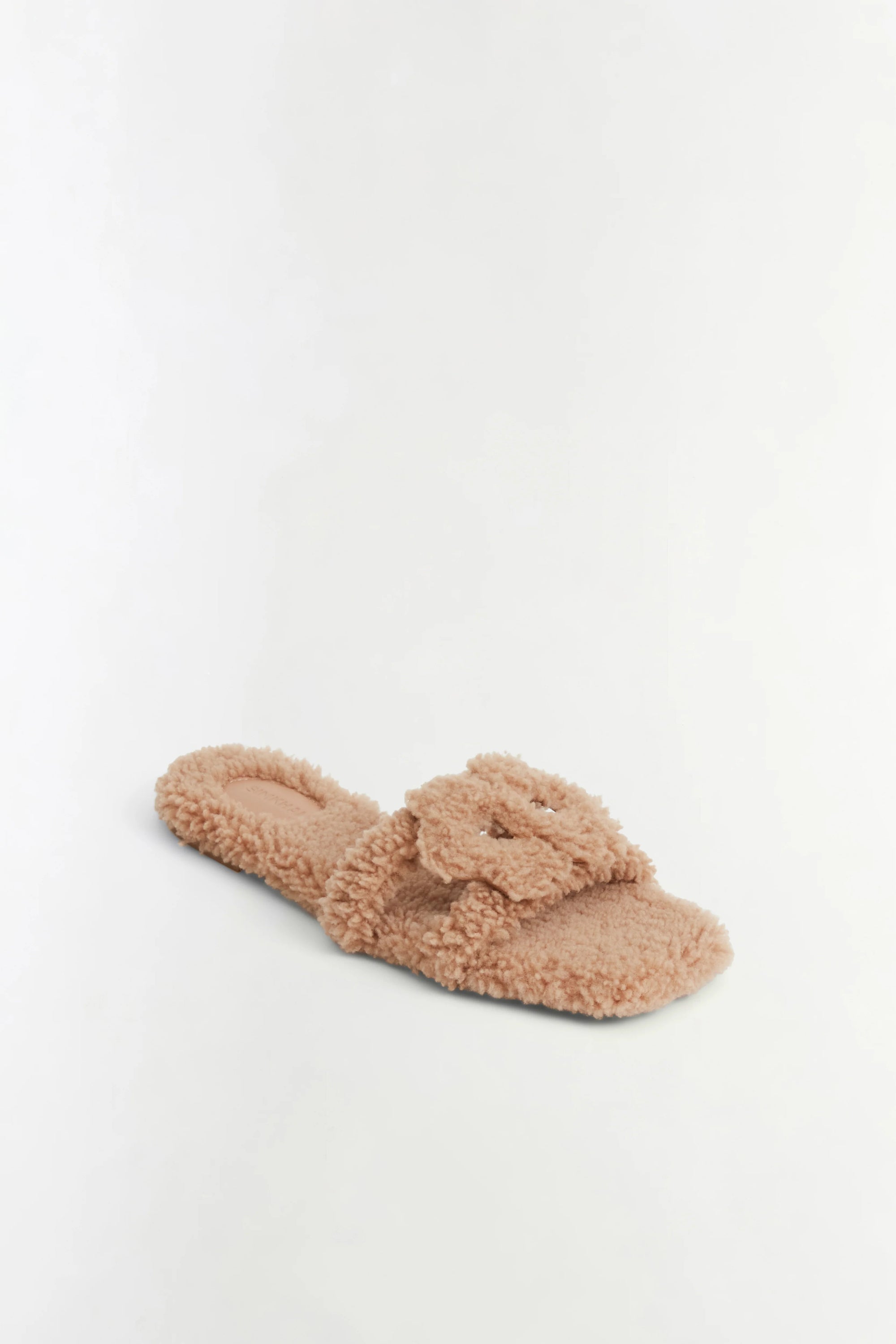 A single fluffy teddy-texture slide sandal in a warm beige or light tan color, photographed on a clean white studio background.