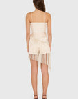 model wearing a cream colored romper with fringe scarf detail, back view