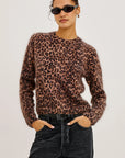 Person wearing a leopard print sweater and black pants on a plain background