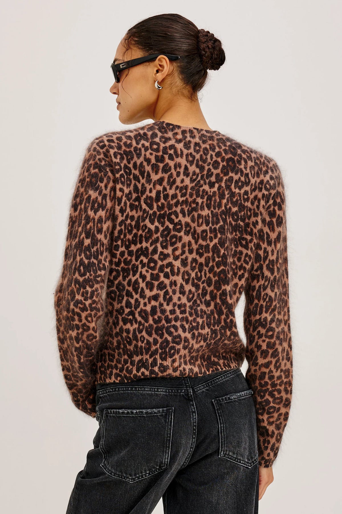Person wearing a leopard print top and black pants on a plain background