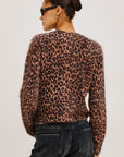 Person wearing a leopard print top and black pants on a plain background