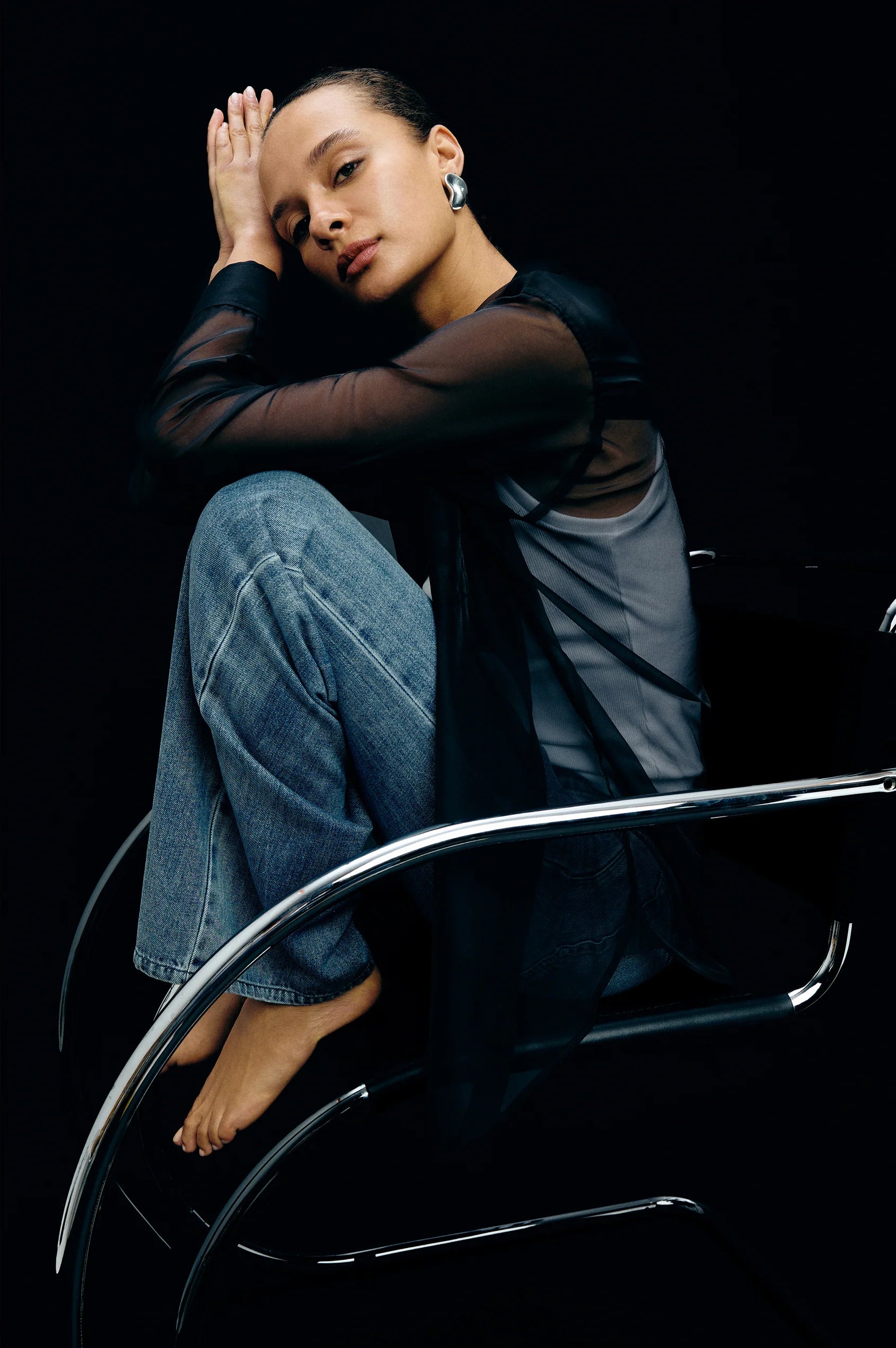 Person sitting on a chair with a black background wearing the Sofiya Sheer Top