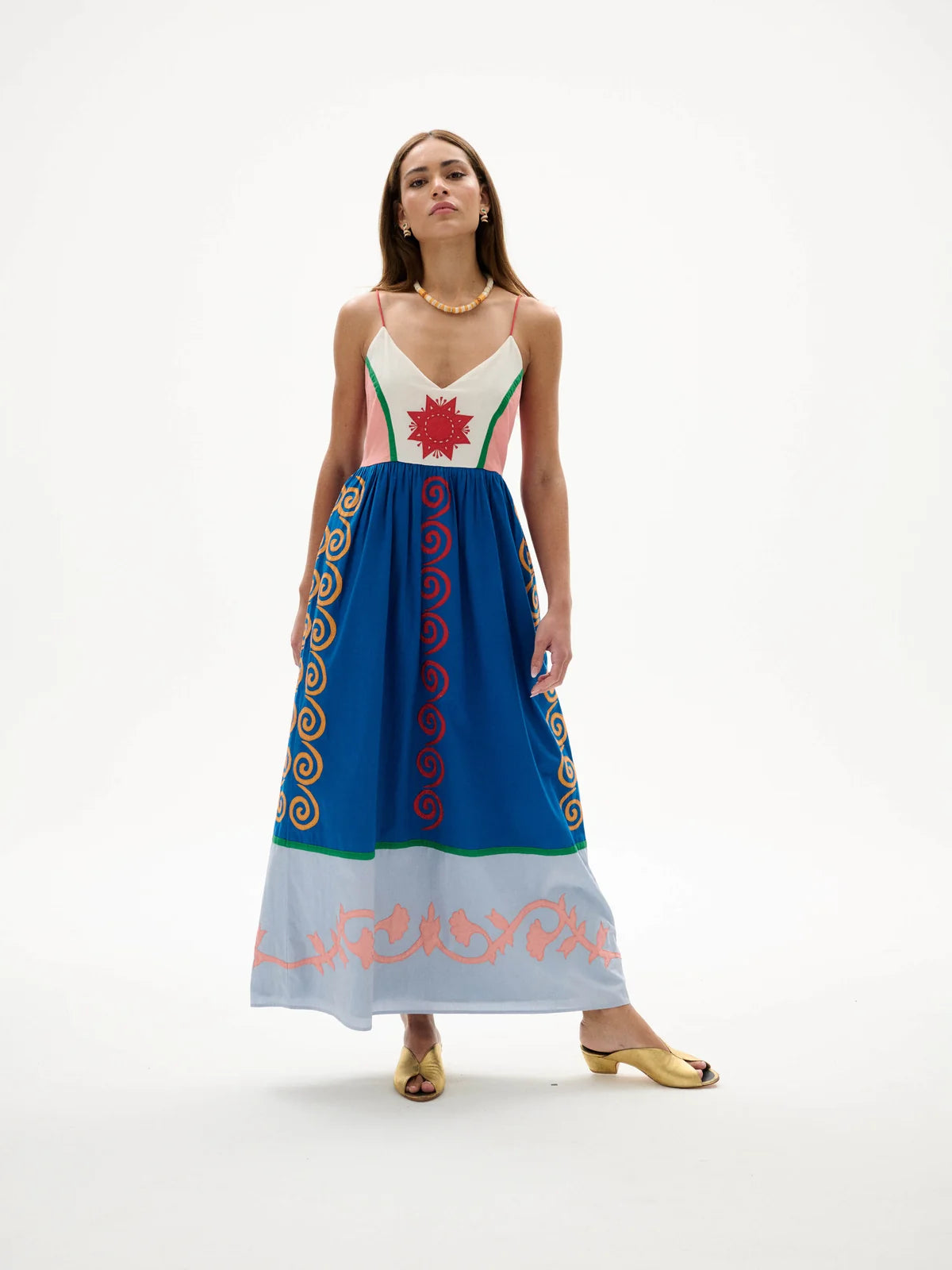 Woman wearing a colorful dress with intricate patterns on a white background