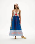 Woman wearing a colorful dress with intricate patterns on a white background