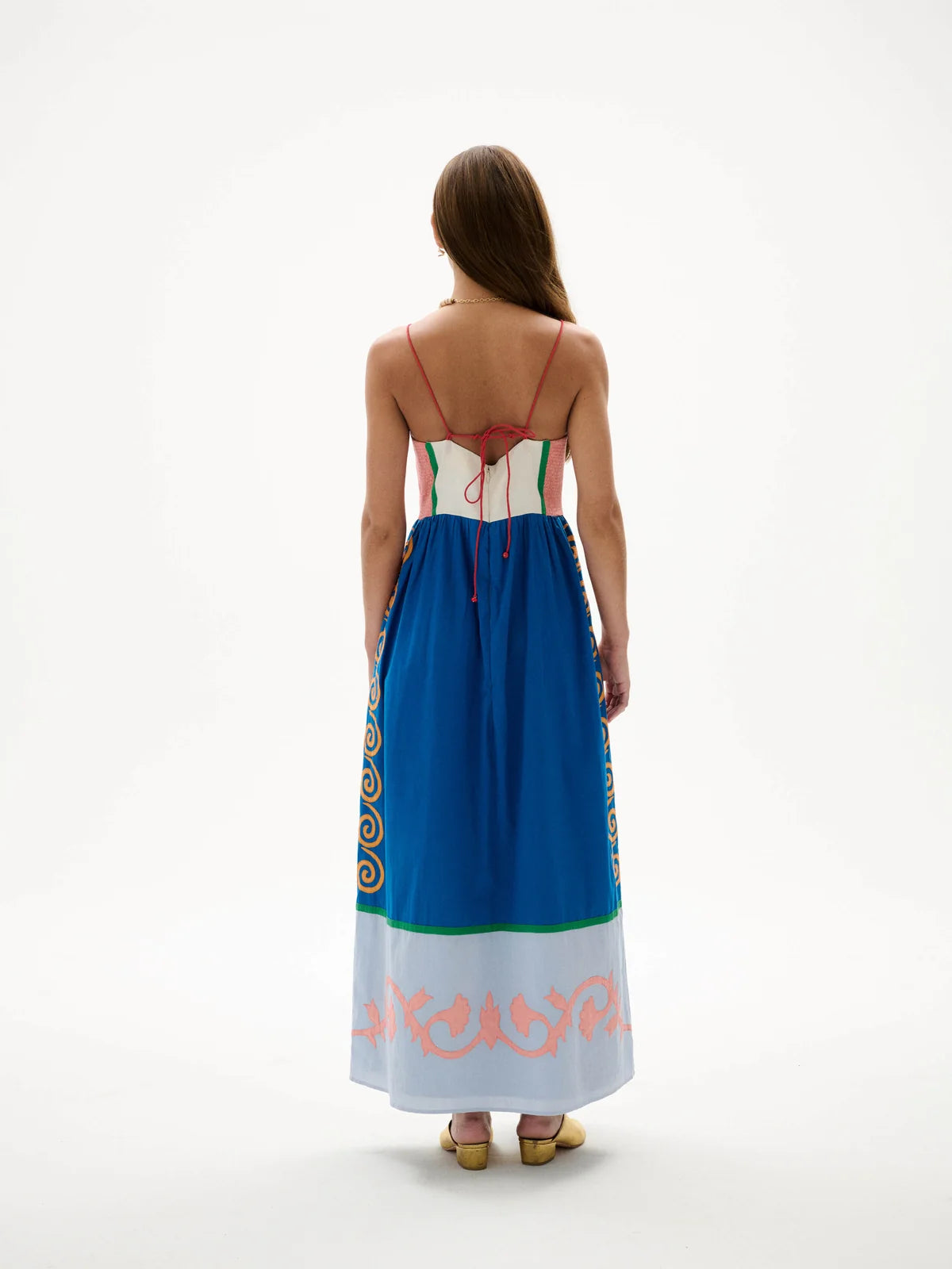 Woman wearing a colorful dress with patterns on a white background, back