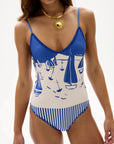 Woman wearing a blue and white swimsuit with sailboat design on a white background