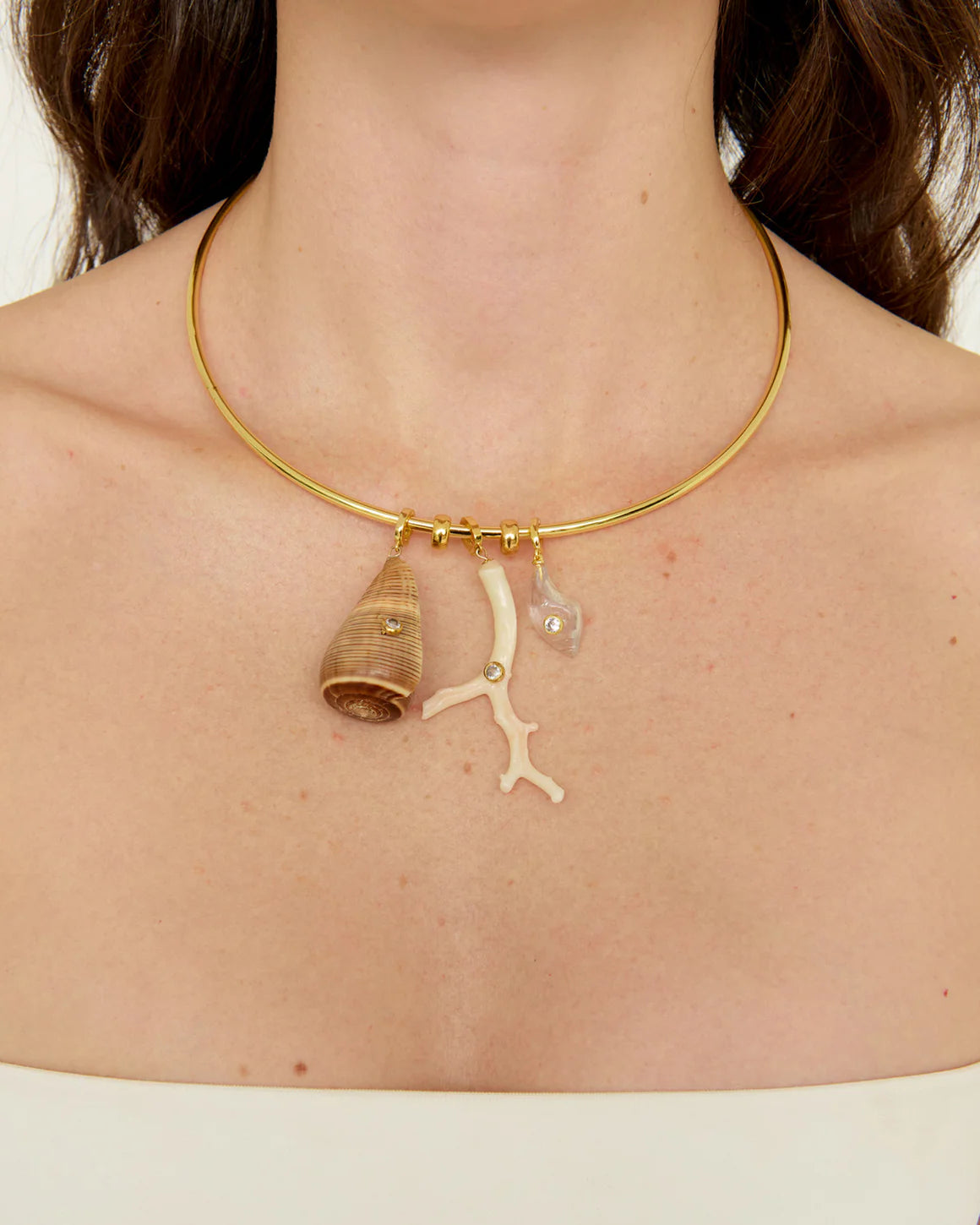 Gold necklace with shell and coral pendant on a person's neck