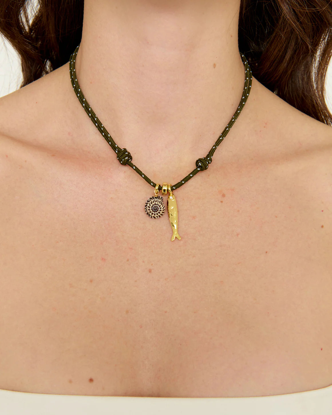 Necklace with a gold fish pendant on a person's neck