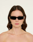 Woman wearing black sunglasses and gold earrings on a white background