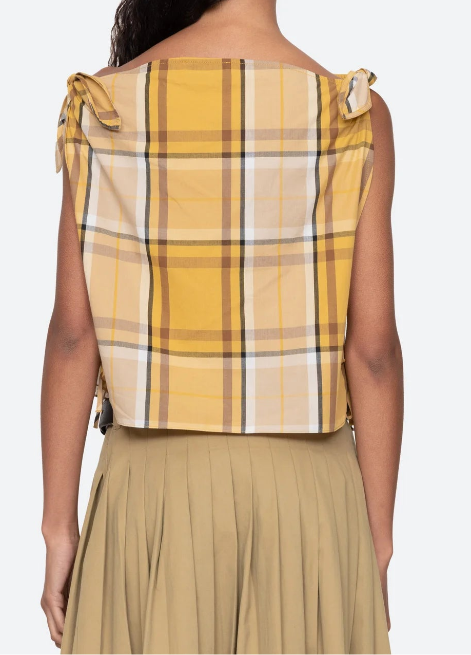 Woman wearing a yellow plaid top with bow details on a white background