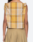 Woman wearing a yellow plaid top with bow details on a white background