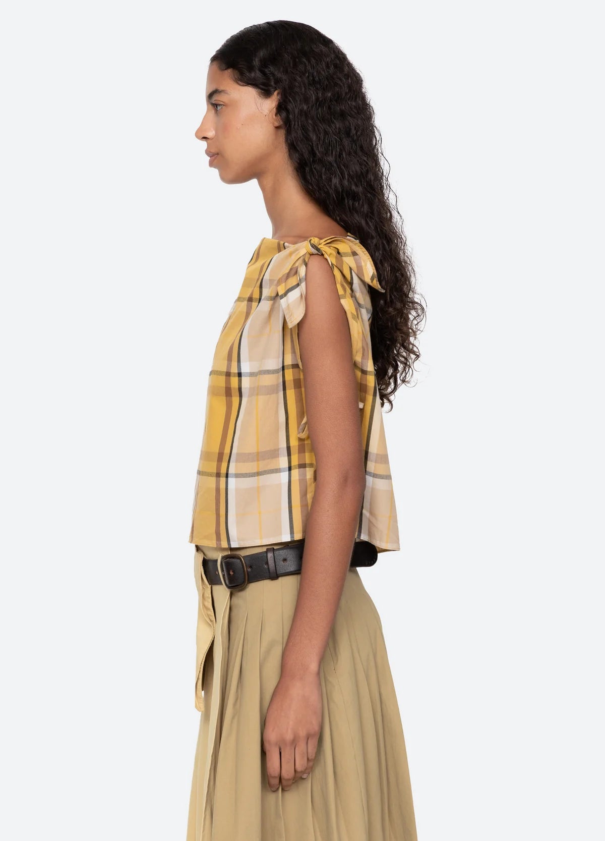 Woman wearing a yellow plaid top and beige skirt on a white background