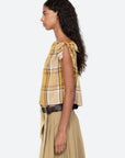 Woman wearing a yellow plaid top and beige skirt on a white background