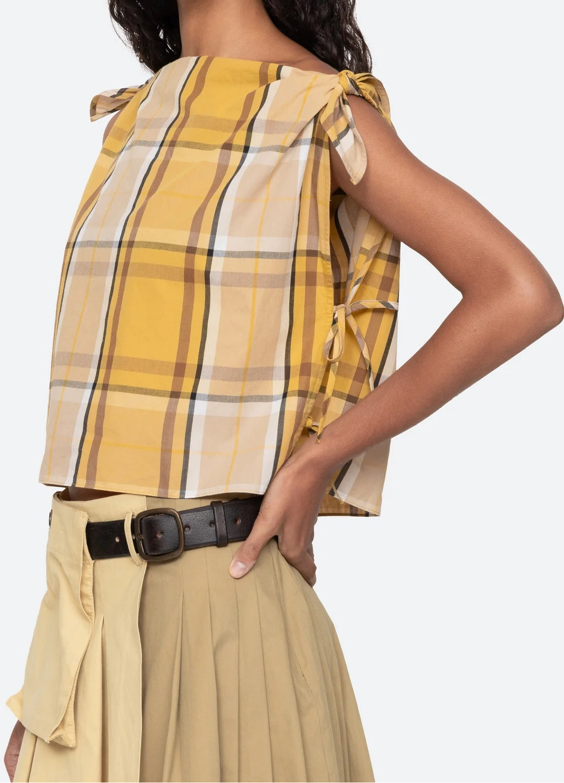 Woman wearing a yellow plaid top and beige skirt on a white background