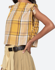 Woman wearing a yellow plaid top and beige skirt on a white background