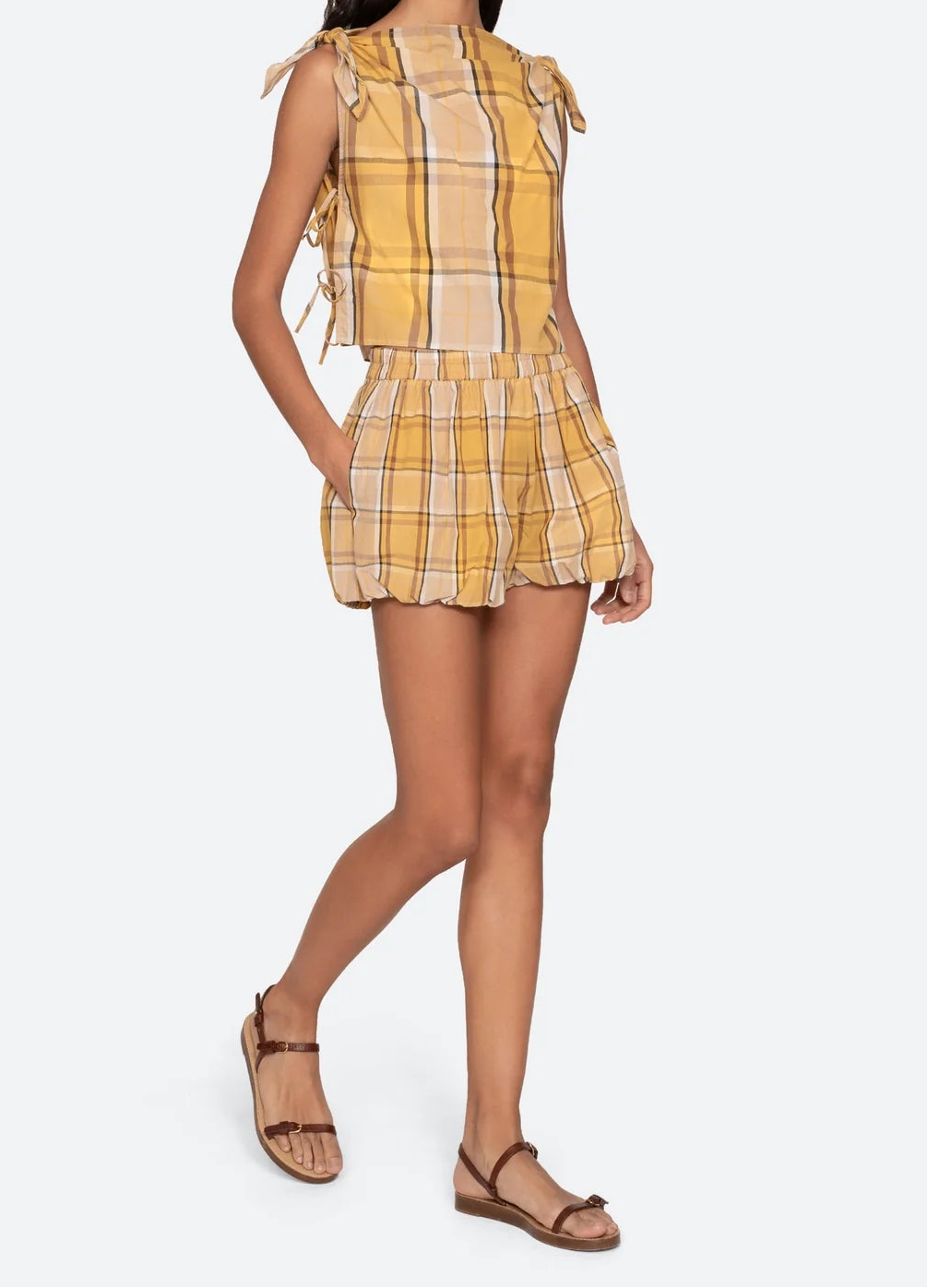 Woman wearing a yellow plaid dress on a white background