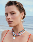 Woman wearing a colorful beaded necklace with silk cord necklace and earrings with a beach background