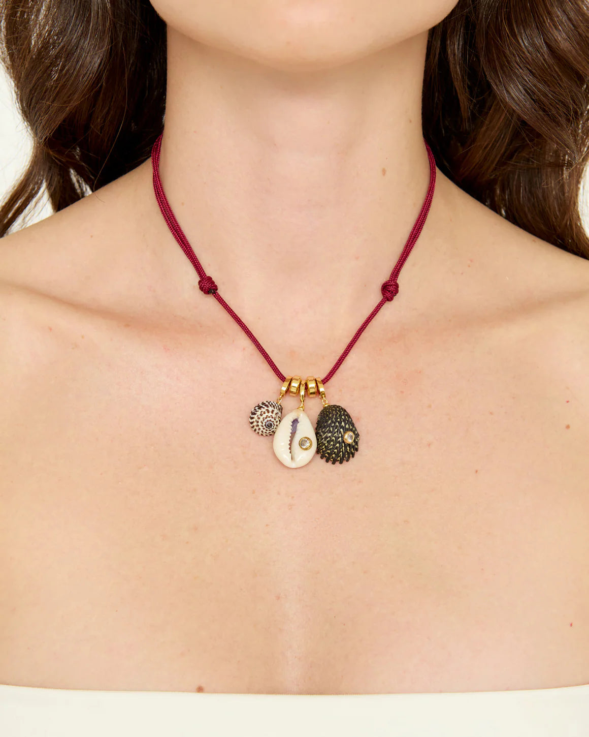 Necklace with three charms on a red cord worn by a person